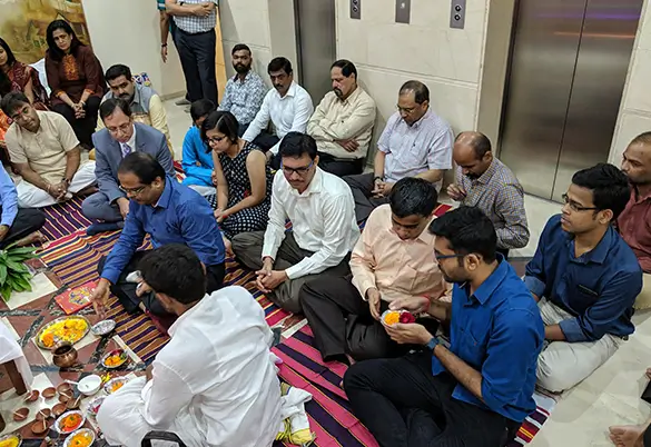 Prism Johnson employees participating in an office pooja ceremony and sitting together during the ritual